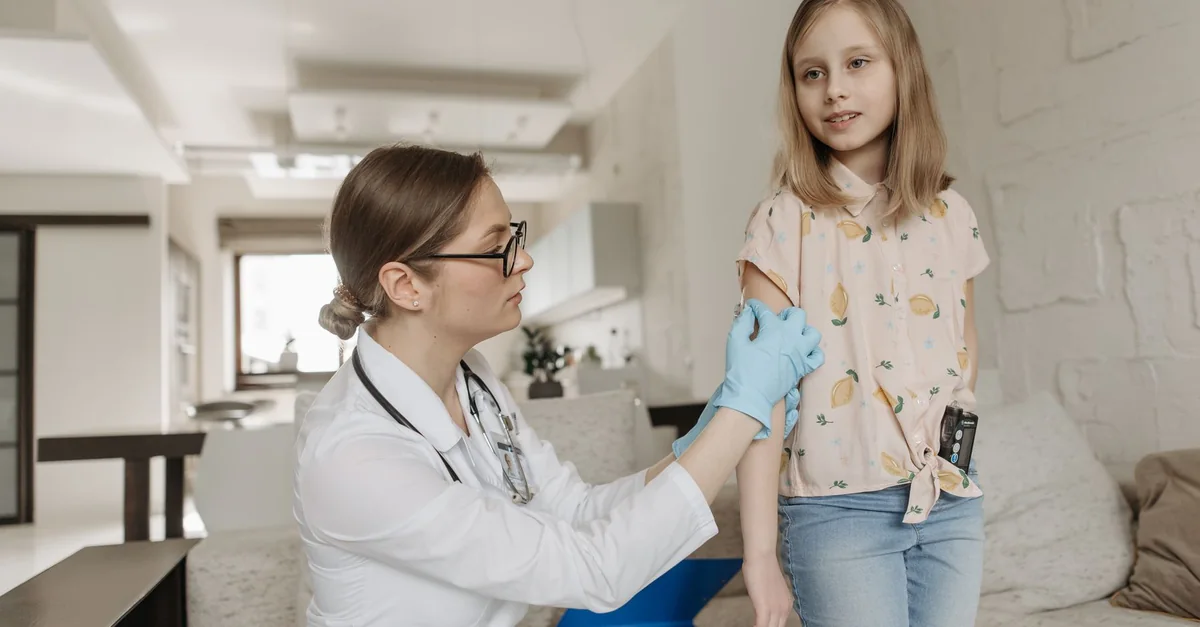 A pediatrician checks a child's arm during a home visit focusing on diabetes management.