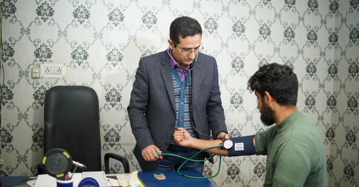 Doctor checking patient's blood pressure during medical consultation indoors.