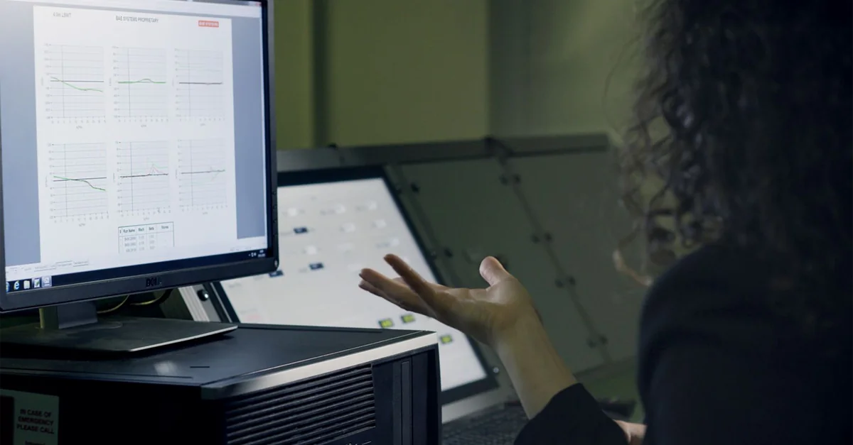 A woman analyzes data on a computer screen in a modern office setup, focusing on technological research.
