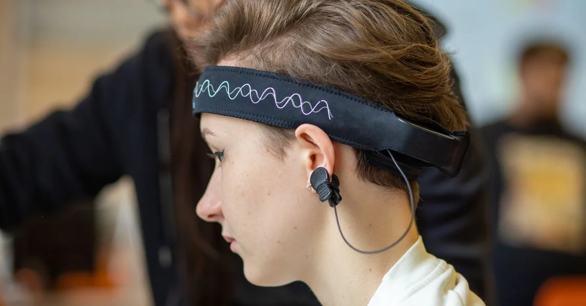 Close-up of a young woman wearing an EEG headband, showcasing modern technology indoors.