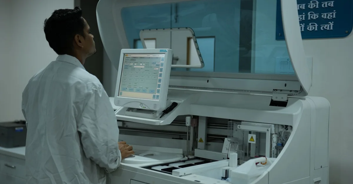 A lab technician operates a clinical analyzer in a modern laboratory setting.