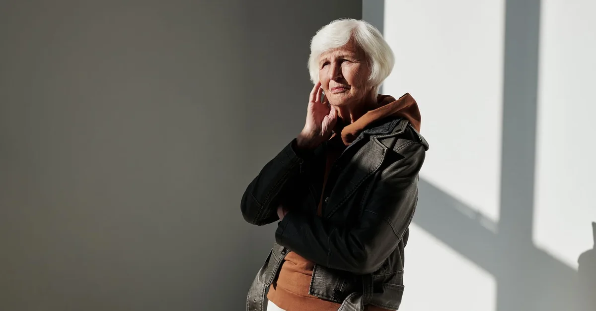 Senior woman posing in a black leather jacket with soft lighting indoors.