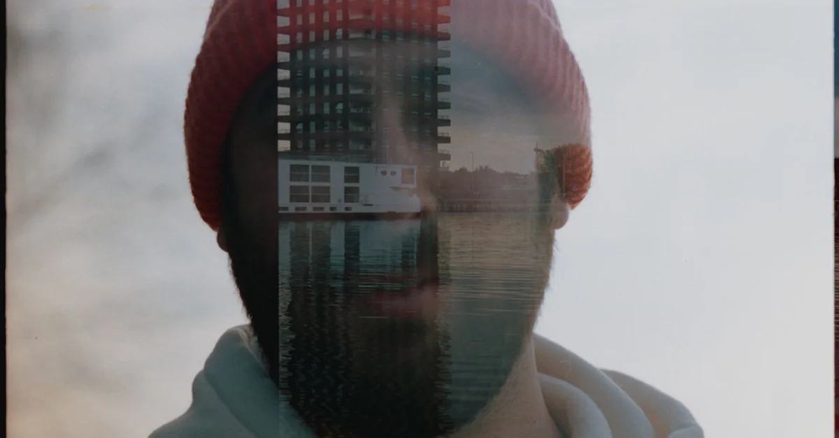 Creative double exposure of a bearded man with urban buildings in a soft light setting.