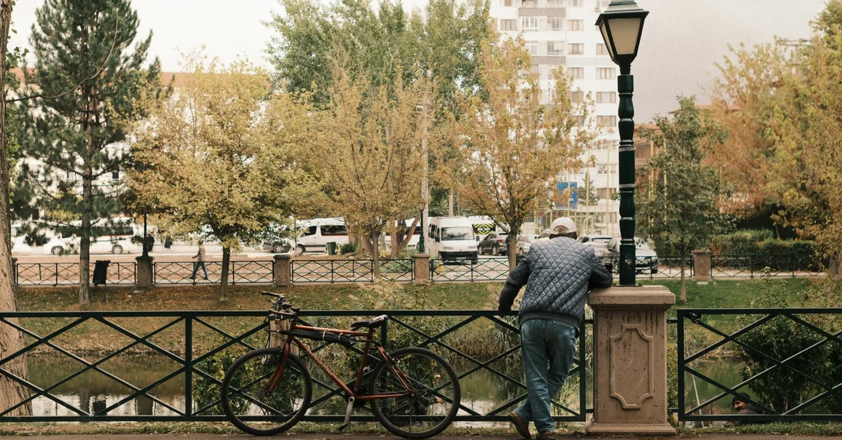 A man leans on railing beside a bicycle, capturing the tranquility of Eskişehir.